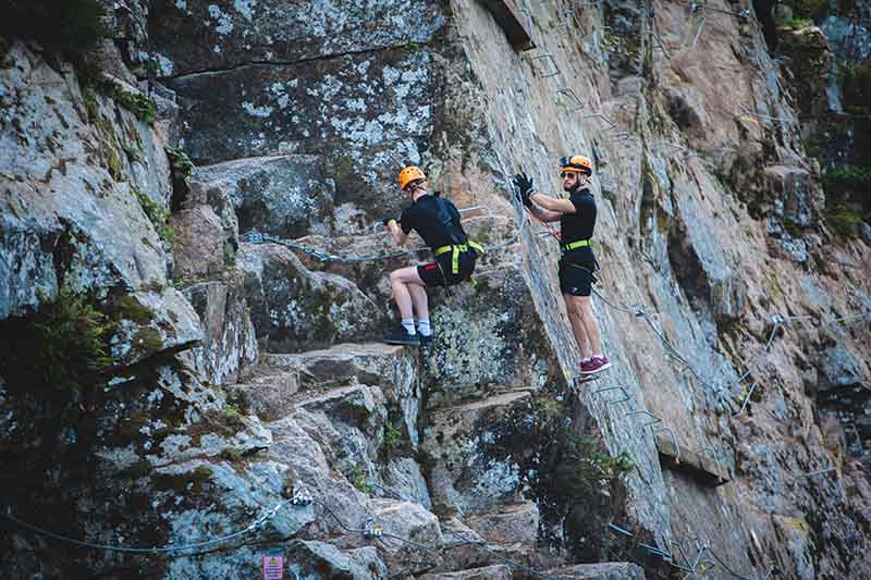 People climbing the iron stairway up a quarry wall at Via Ferrata Cornwall