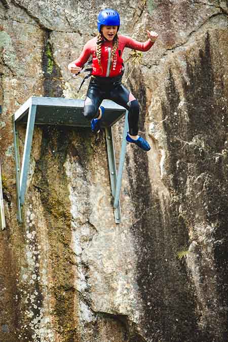 Girl leaping into water in a coasteering session at Via Ferrata Cornwall