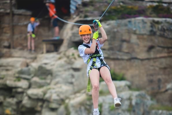 Girl soaring through the air on Via Ferrata Cornwall's zip wire