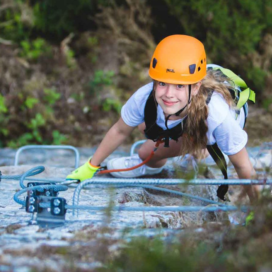 Girl smiling whilst scaling cliff face at Via Ferrata Cornwall