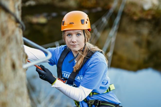 Teenage girl climbing the cliff face at Via Ferrata Cornwall
