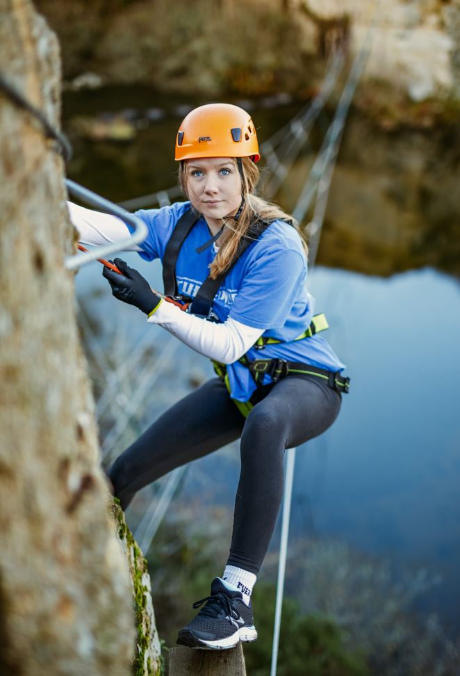 Teenage girl climbing the cliff face at Via Ferrata Cornwall